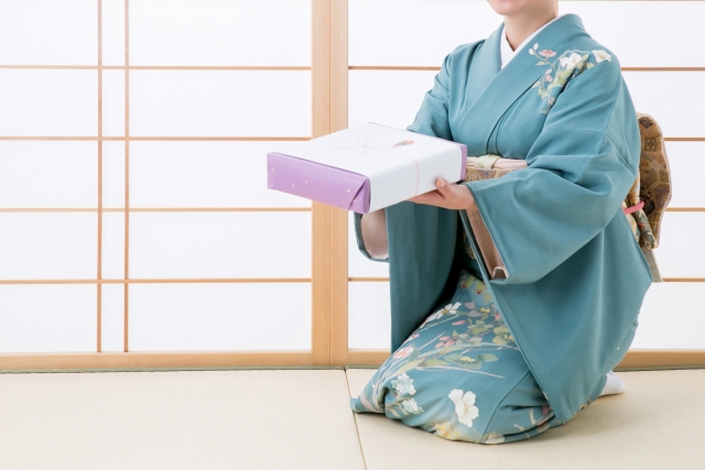 お中元を渡す和服の女性